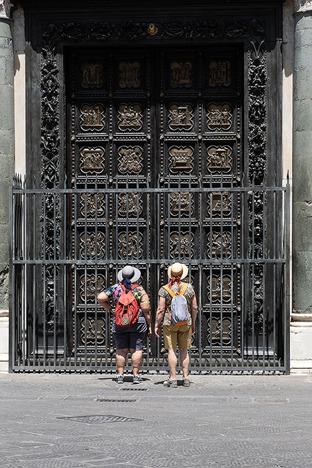 2 Touristen mit Rucksack stehen vor hohem schwarzen Tor einer Kirche Italien - Janet Große Fotografin