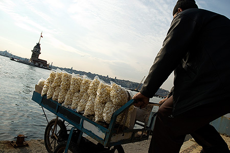 Man mit Popcorn auf einen Farradkarren vor einem Fluss- Janet Große Fotografin Streetphotography